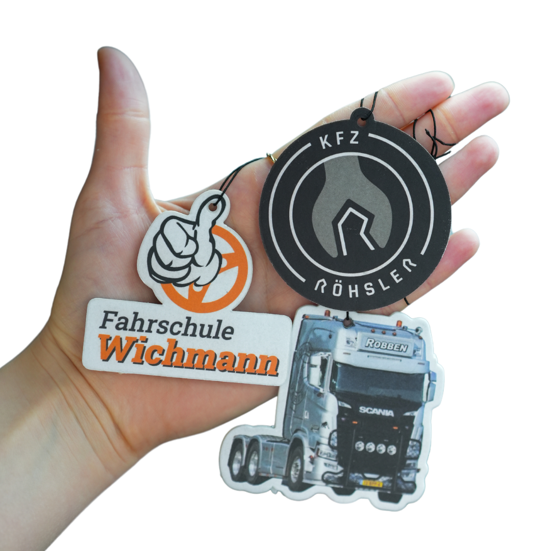 Drei individuell gestaltete SNIFFCAR Duftbäume mit Kundenlogos in einer Hand